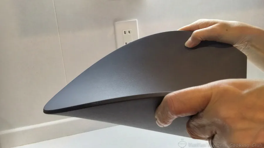 手でしならせて柔軟性を見せているエラストマー製のD型まな板